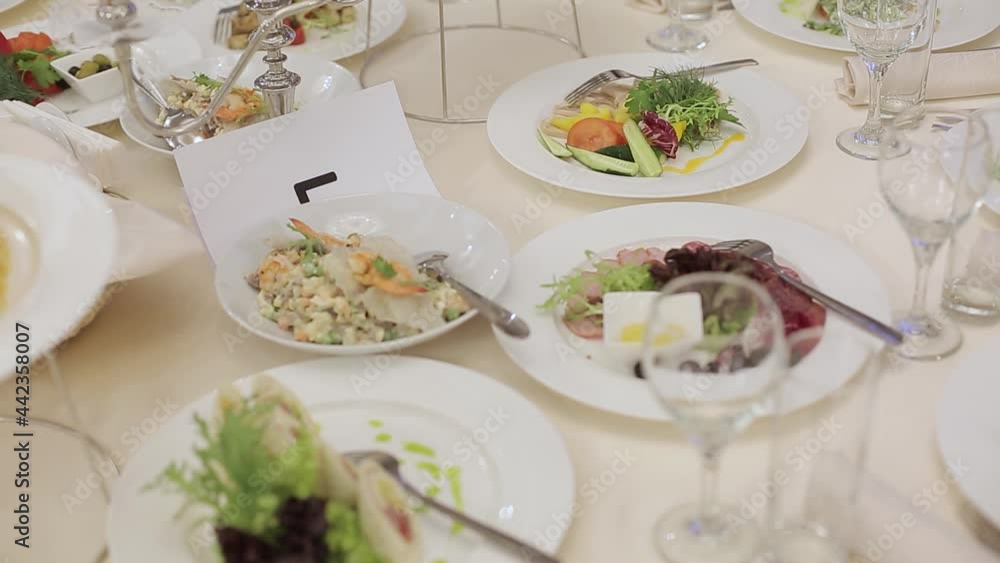 The waiter serves dishes to put on the table in the restaurant. Male waiter in a restaurant puts plates of hot meat dish on the table The waiter serves dishes to put on the table in the restaurant. Male waiter in a restaurant puts plates of hot meat dish on the table