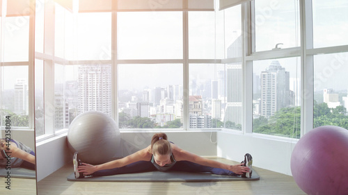 Young attractive woman practicing yoga at the gym with nice city view  stretching in upward facing dog exercise  Urdhva mukha shvanasana pose  working out    indoor full length  living room