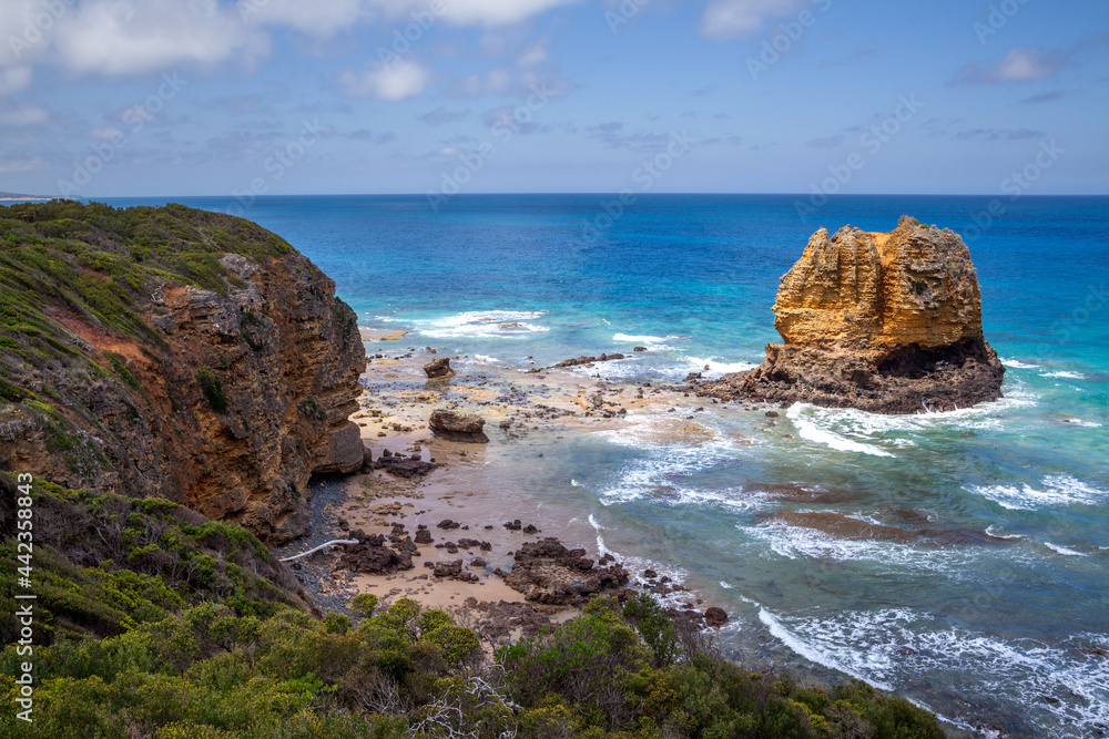 View from above on a large rocky reef of large ocean waves. Blue panorama on a beautiful steer rocky shore, sandy beaches and a huge brown rock protruding from the water. Australia. Great Ocean Road. 