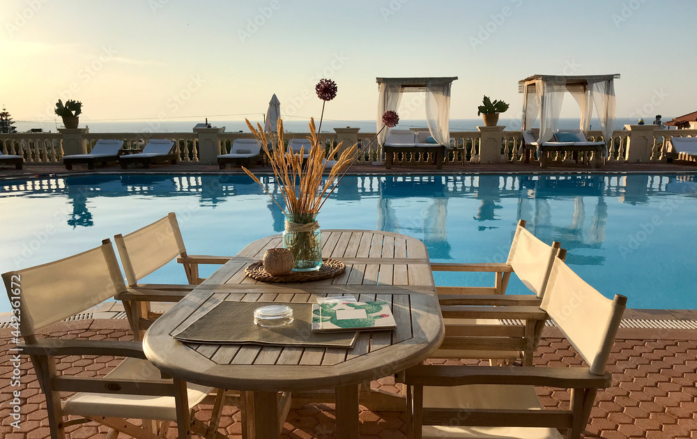 Fototapeta premium Crete, Greece, Europe. 2019. A poolside restaurant table for four customers, table and directors chairs.