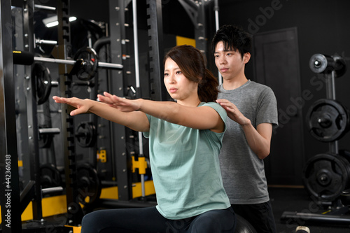 トレーニングをするアジア人女性と補助をする男性トレーナー