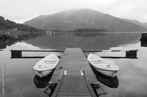 Symmetrical black and white image of two small docked boats in Balestrand Norway. photo