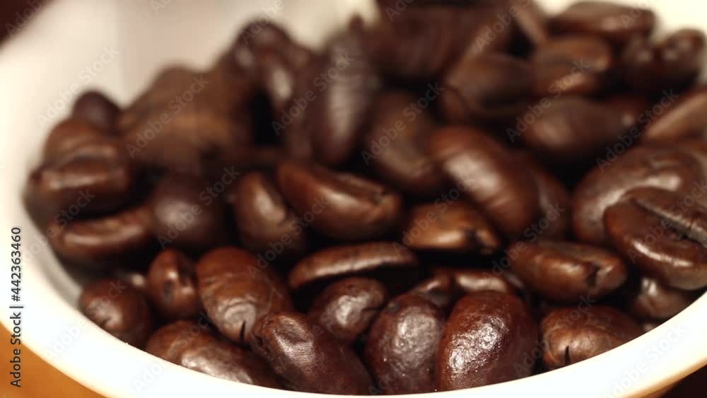 Macro close up of coffee beans falling into a white bowl Macro close up of coffee beans falling into a white bowl