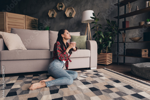 Portrait of attractive dreamy girl sitting on carpet drinking latte resting pastime day at modern loft industrial home indoors photo