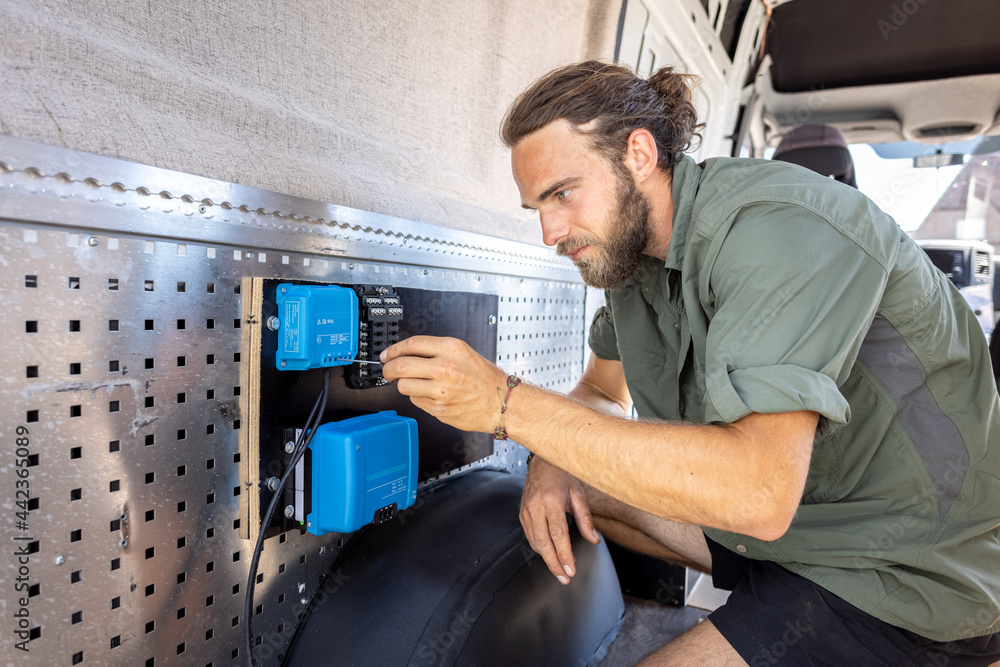 Man connecting electronics in a camper van Man connecting electronics in a camper van