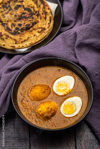 Fried egg curry or Anda Masala served in a bowl with  lachha parantha