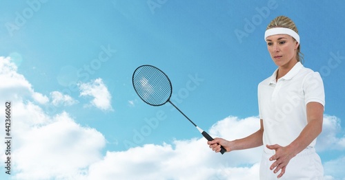 Caucasian female badminton player holding racket against clouds in blue sky © vectorfusionart