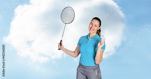 Portrait of caucasian female badminton player holding racket smiling against clouds in blue sky