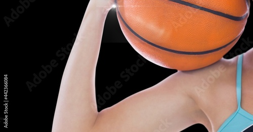 Close up view of female athlete holding a basketball against black background