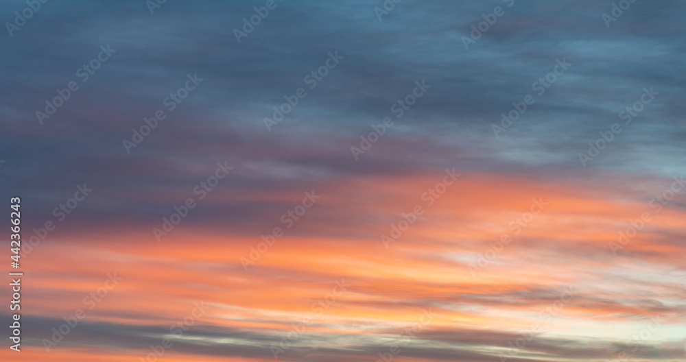 Colorful photo of sky highlighted by red orange sunset on dark blue sky, soft colors. Nice real image to use as background picture