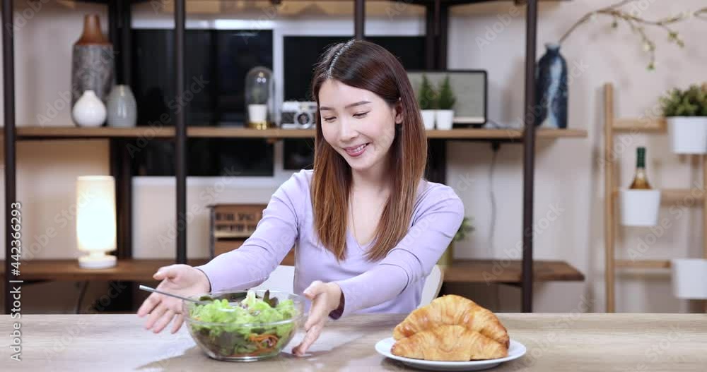 Asian woman refuses to eat her favorite bread and opts for a healthy salad Asian woman refuses to eat her favorite bread and opts for a healthy salad