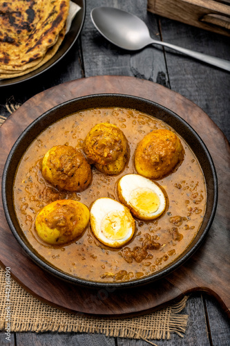Fried egg curry or Anda Masala served in a bowl with lachha parantha