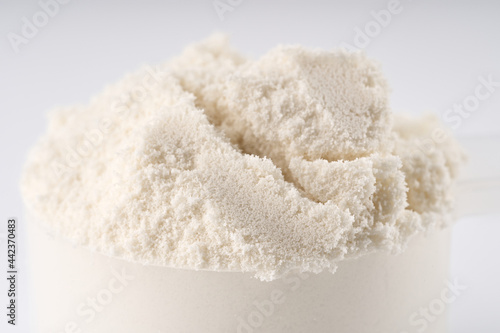 Heap of protein powder on white background. Scoops Of Protein Powder. Measuring spoon and heap of vanilla protein powder.