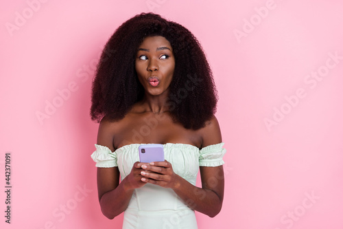 Photo of young attractive afro girl amazed shocked surprised pouted lips use smartphone isolated over pink color background