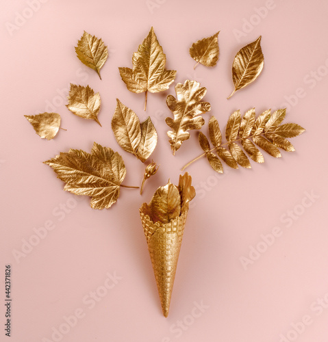 Wall Art. Botanical set. Lifestyle decoration. Gold ice cream cone with autumn gold leaves, on pink background. Flat lay. Top view. Beautiful composition with leaves in bright golden paint