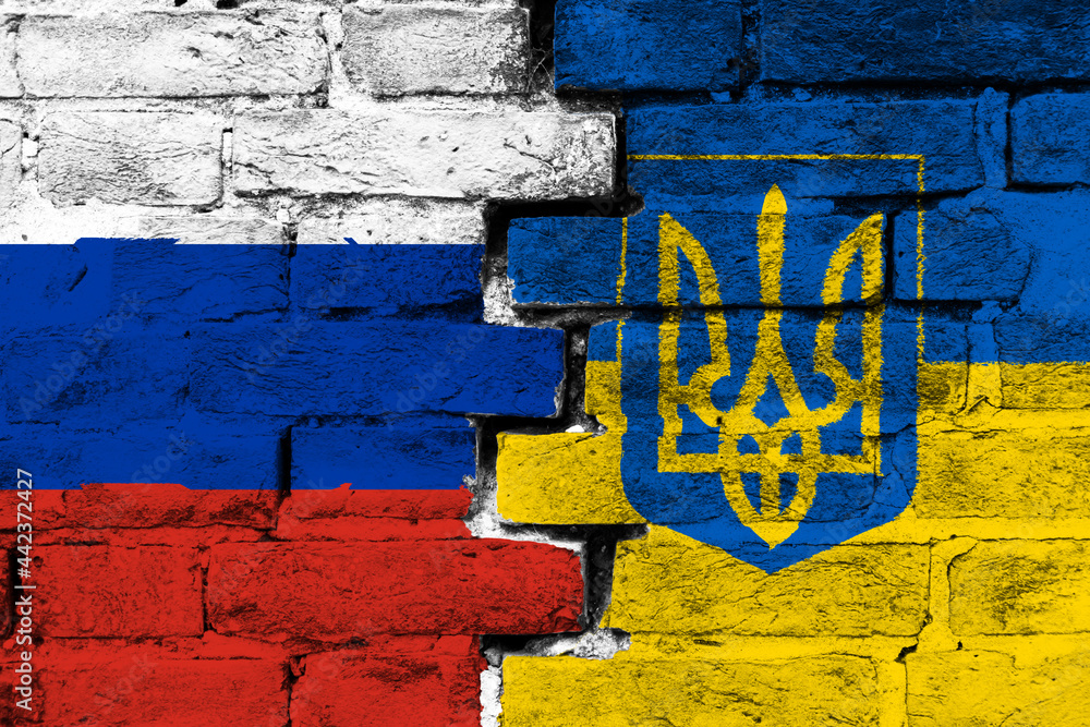 Concept of the relationship between Russia and Ukraine with two painted flags on a damaged brick wall