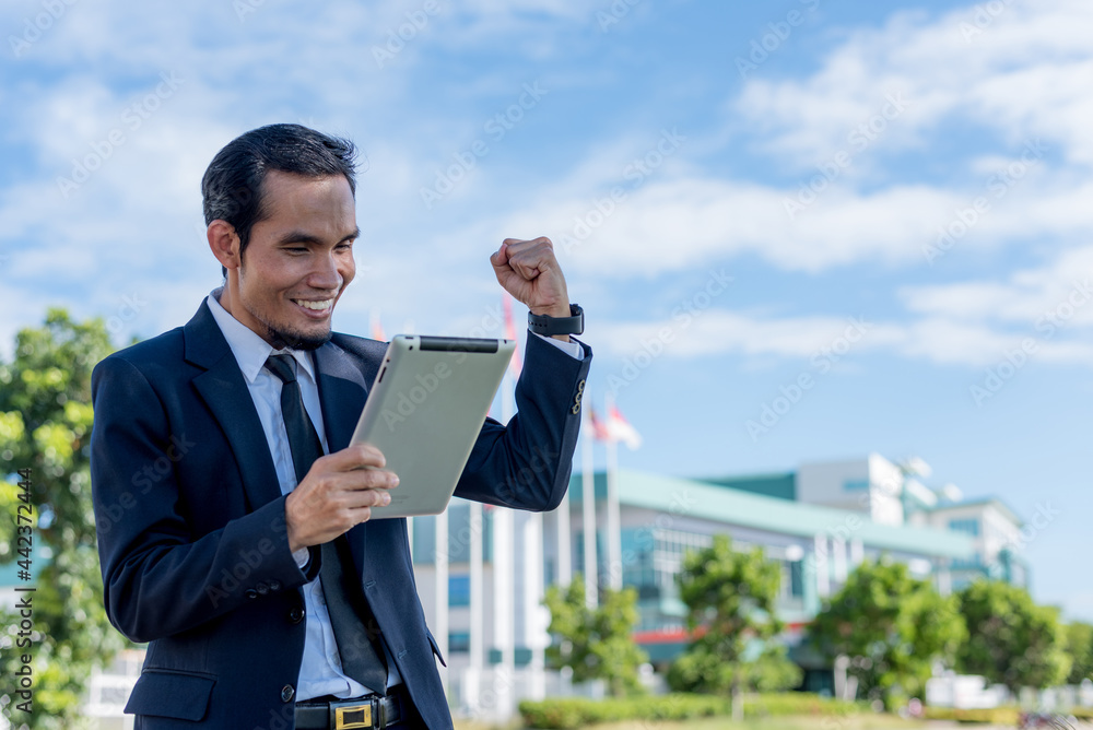 Happy Asian businessman looking at tablet with smile and delighted Happy Asian businessman looking at tablet with smile and delighted