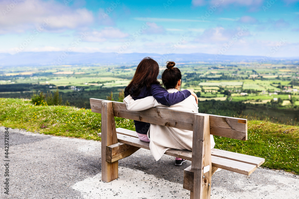 Two friends sitting in a bench near the edge of the road at Vee Pass in the Knockmealdown mountains in Clogheen county Tipperary, Ireland