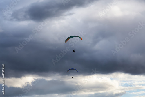 Adventurous People Flying on a Paraglider around the mountains. Savona, British Columbia, Canada.