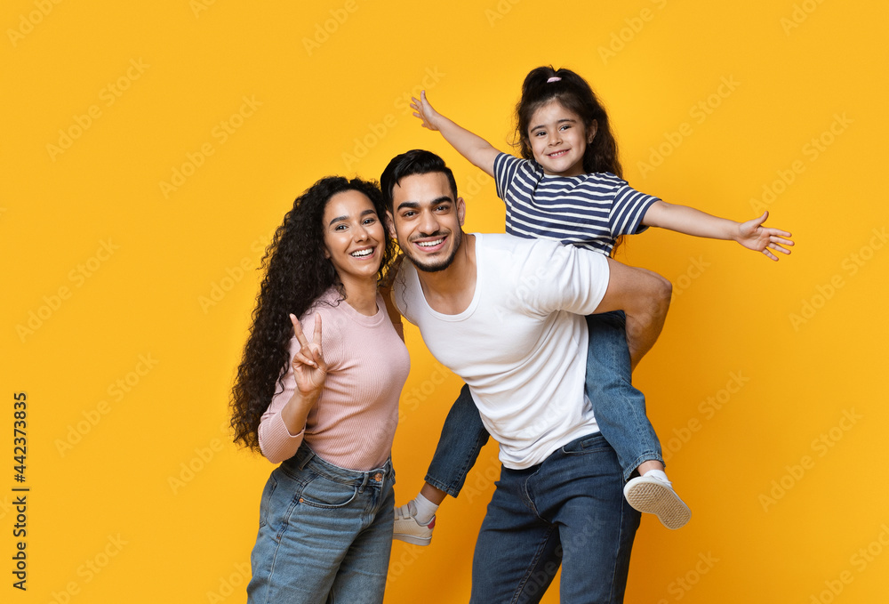Portrait Of Joyful Arab Family With Little Daughter Posing Over Yellow Background Portrait Of Joyful Arab Family With Little Daughter Posing Over Yellow Background