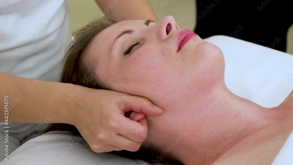 Middle-aged woman getting her ears massage. A middle-aged woman is given a therapeutic ear massage. Relaxing massage for wellness in the spa salon Middle-aged woman getting her ears massage. A middle-aged woman is given a therapeutic ear massage. Relaxing massage for wellness in the spa salon