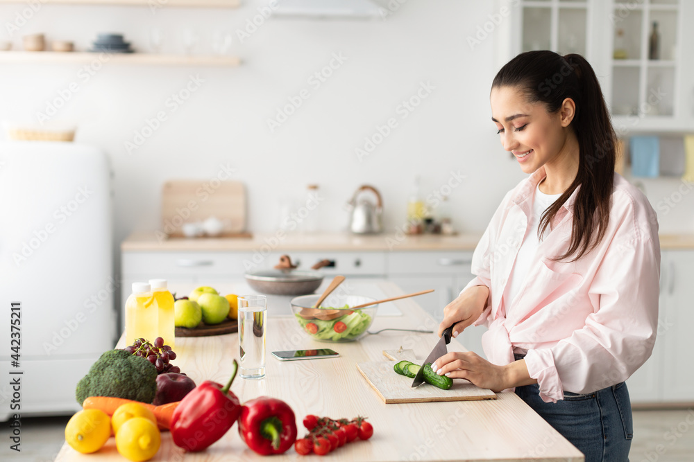 Portrait of smiling young lady cooking fresh salad