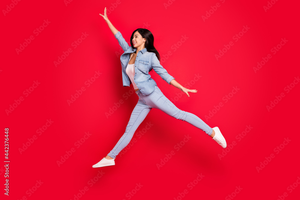 Full length body size view of attractive fit cheerful girl jumping having fun striving isolated over bright red color background