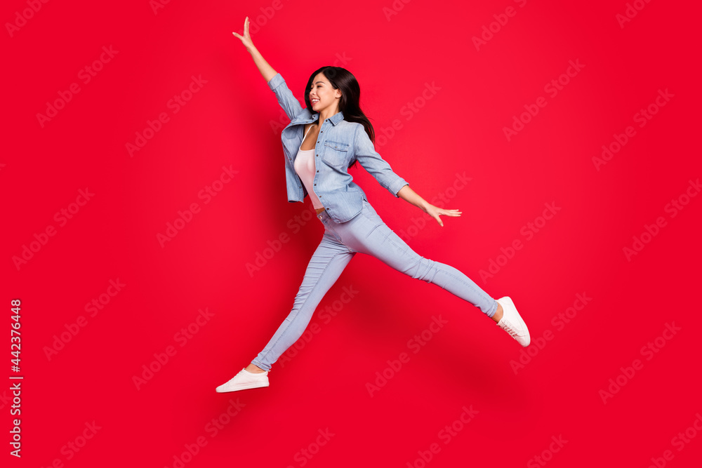 Full length body size view of attractive fit cheerful girl jumping having fun striving isolated over bright red color background Full length body size view of attractive fit cheerful girl jumping having fun striving isolated over bright red color background