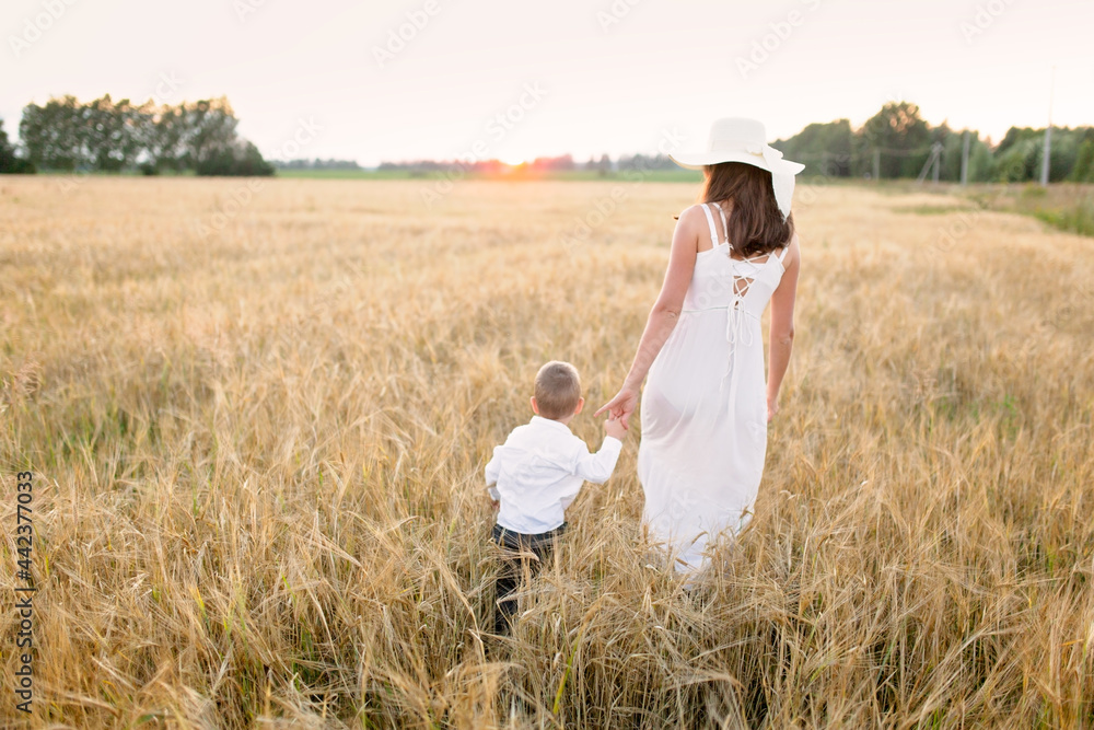 Motherhood. Toddler toddler boy with mom in a field at sunset in summer, beautiful summer photo, blur and soft focus, very warm photo, toning Motherhood. Toddler toddler boy with mom in a field at sunset in summer, beautiful summer photo, blur and soft focus, very warm photo, toning