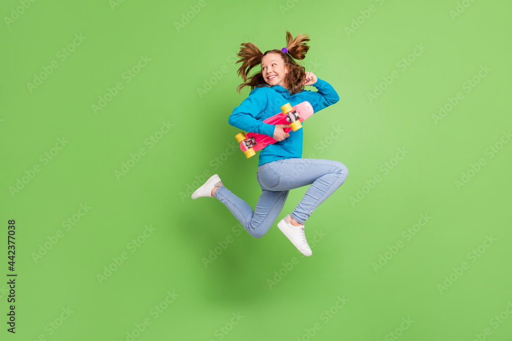 Full body photo of ponytail brown haired little girl jump wear casual street clothes jump skater run isolated on green color background Full body photo of ponytail brown haired little girl jump wear casual street clothes jump skater run isolated on green color background