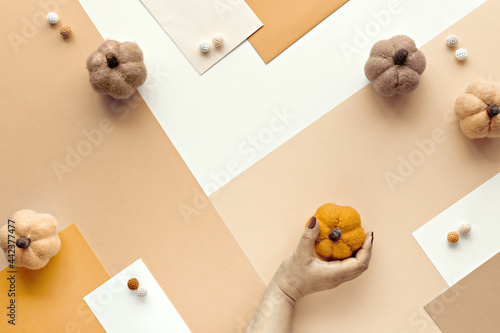 Sepia flat lay with felt pumpkins. Creative knitting hobby. Concept background in orange, beige, off white, brown earh shades. Seasonal Autumn, Fall arrangement on neutral layered paper background. photo