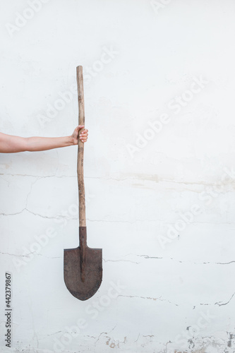 Shovel in a woman's hand. Girl holding garden equipment in hands on white background