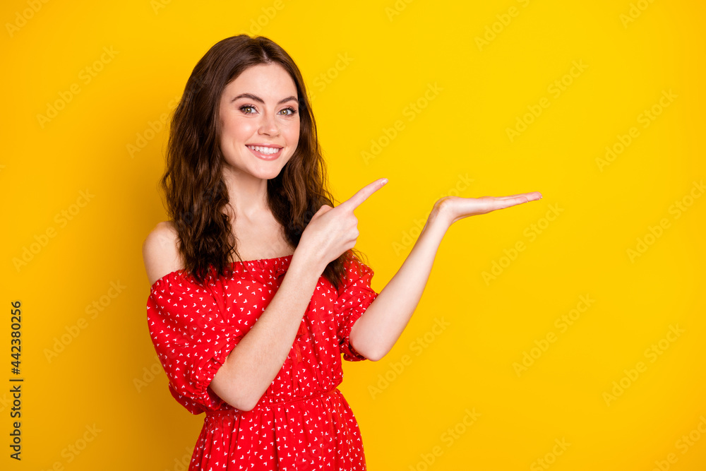 Photo portrait of happy girl in red dress pointing finger on palm keeping blank space isolated vibrant yellow color background Photo portrait of happy girl in red dress pointing finger on palm keeping blank space isolated vibrant yellow color background