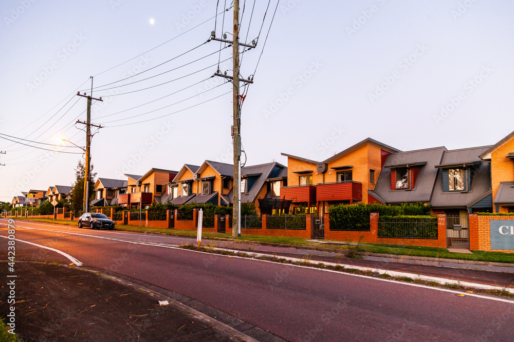 Street scene at dusk of power poles and wires and row of apartments Street scene at dusk of power poles and wires and row of apartments