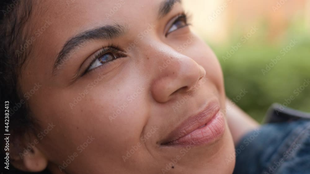 Close-up Appearance of Afro-American Girl with Brown Eyes looking at the sky. Attractive Beauty Face of Mixed-Race Female. Touching Curly Hair standing outdoors. Long Eyelashes. Enjoys Summertime. Close-up Appearance of Afro-American Girl with Brown Eyes looking at the sky. Attractive Beauty Face of Mixed-Race Female. Touching Curly Hair standing outdoors. Long Eyelashes. Enjoys Summertime.