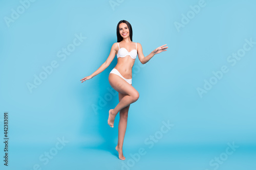 Fototapeta Naklejka Na Ścianę i Meble -  Full size photo of positive brown hairdo lady go wear white lingerie isolated on blue background