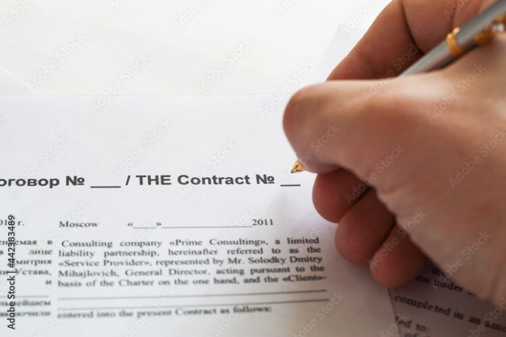 Obraz premium A businessman sitting at an office desk signs a contract with a shallow emphasis on signing. business and finance