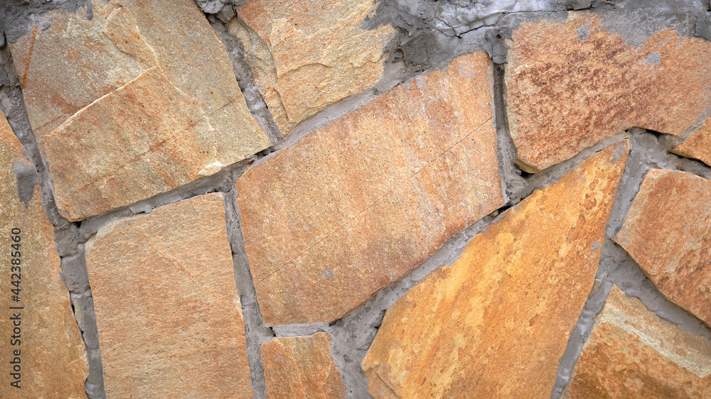 Fototapeta premium Fragment of a wall from a chipped stone, stone wall texture. decorative stone, different colors.