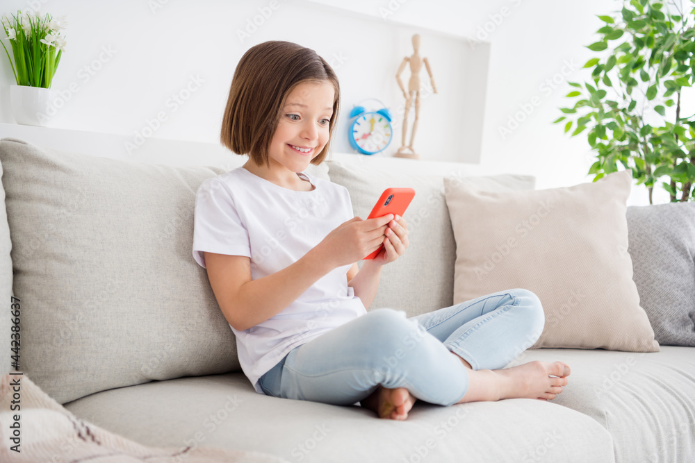 Portrait of attractive cheerful girl sitting on sofa using device gadget app 5g post browsing media staying safe at light flat home indoors Portrait of attractive cheerful girl sitting on sofa using device gadget app 5g post browsing media staying safe at light flat home indoors