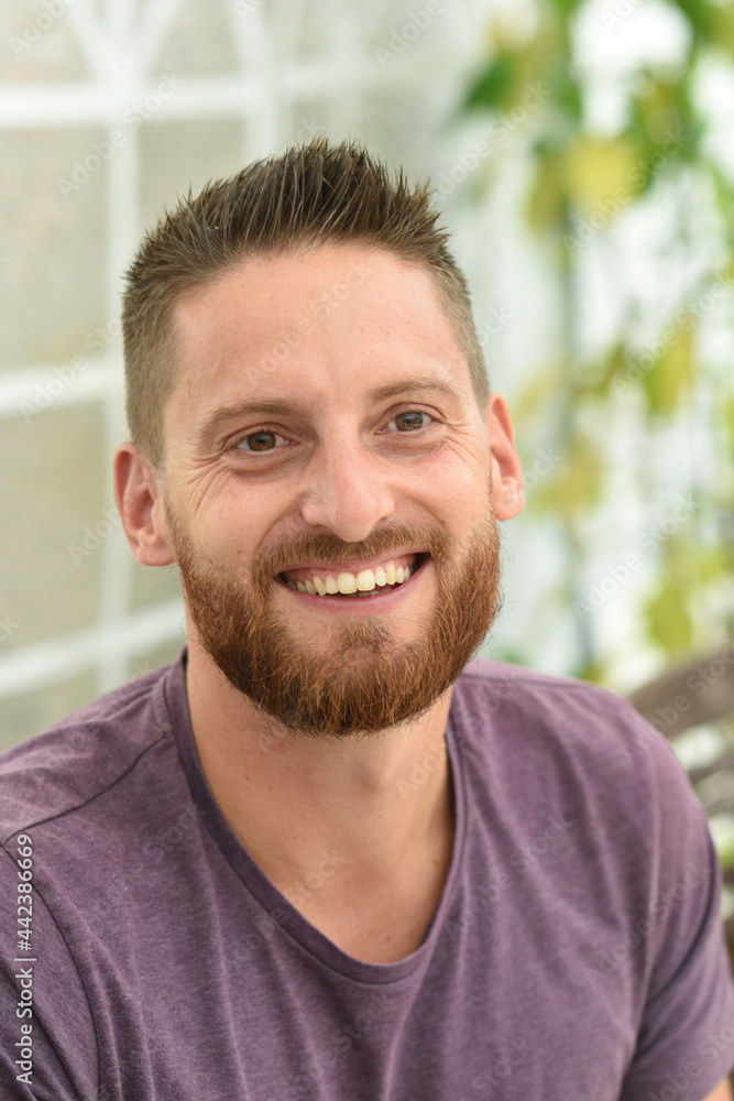 young bearded man smiling with purple clothes young bearded man smiling with purple clothes