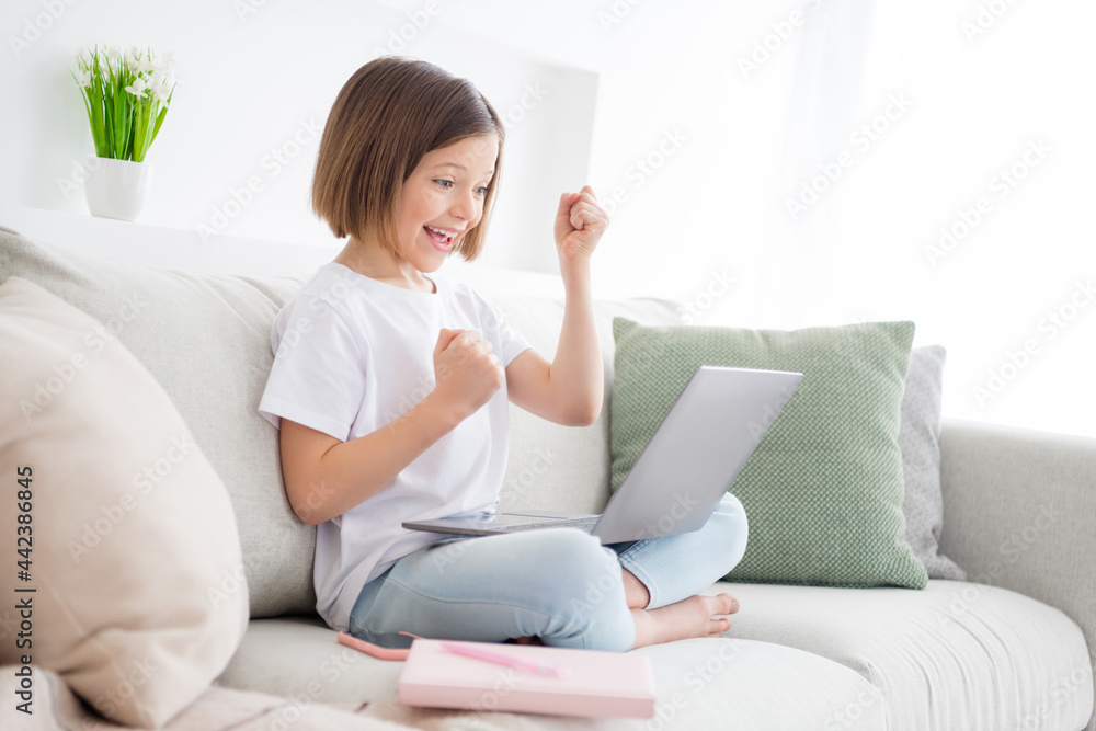 Photo portrait little girl sitting on couch talking on web camera passes test gesturing like winner Photo portrait little girl sitting on couch talking on web camera passes test gesturing like winner