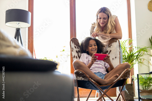 Young girl showing her mother something on a smartphone 
 photo