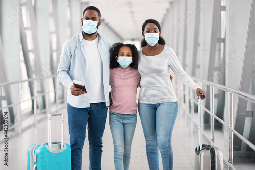 Black family in face masks traveling, posing in modern airport