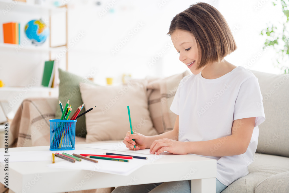 Profile side photo of young cheerful attractive little girl happy positive smile sit sofa draw paint colorful pencils indoors Profile side photo of young cheerful attractive little girl happy positive smile sit sofa draw paint colorful pencils indoors