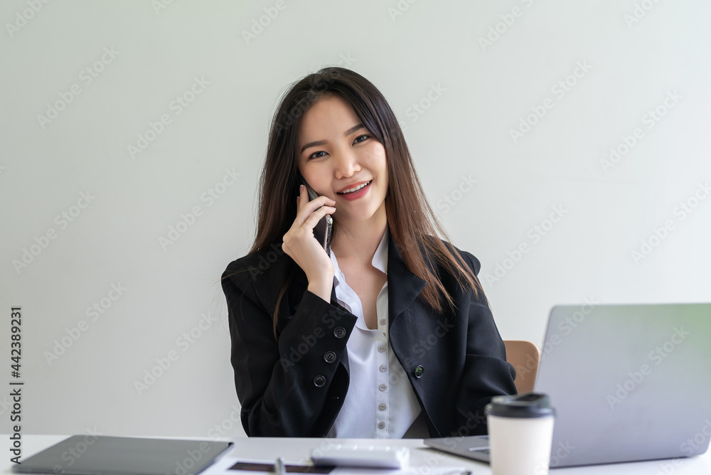 Young businesswoman sitting at work talking on the phone. Looking at the camera. Young businesswoman sitting at work talking on the phone. Looking at the camera.