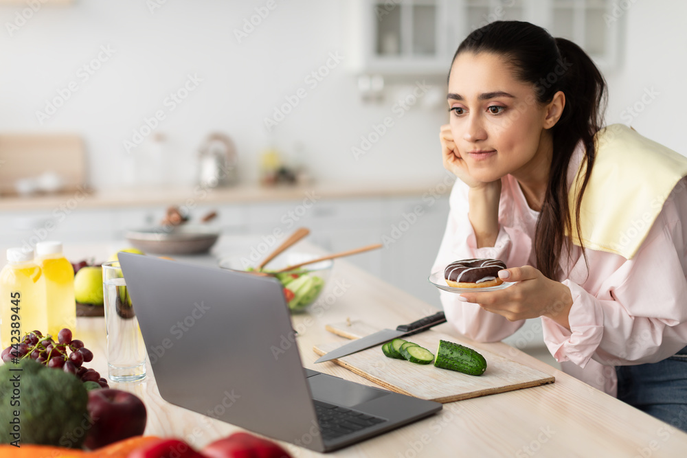 concerned woman watching movie using laptop and eating dessert