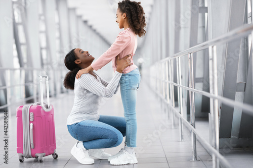 Happy black woman hugging girl kid in airport