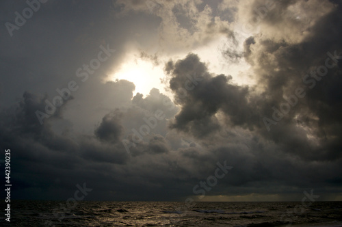 Thick swirling storm clouds fill the sky and surround the sun, obscuring it from view.