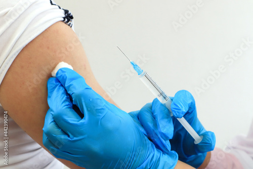 The concept of vaccination among the population. Hands in medical gloves make an injection into a man s hand  close-up