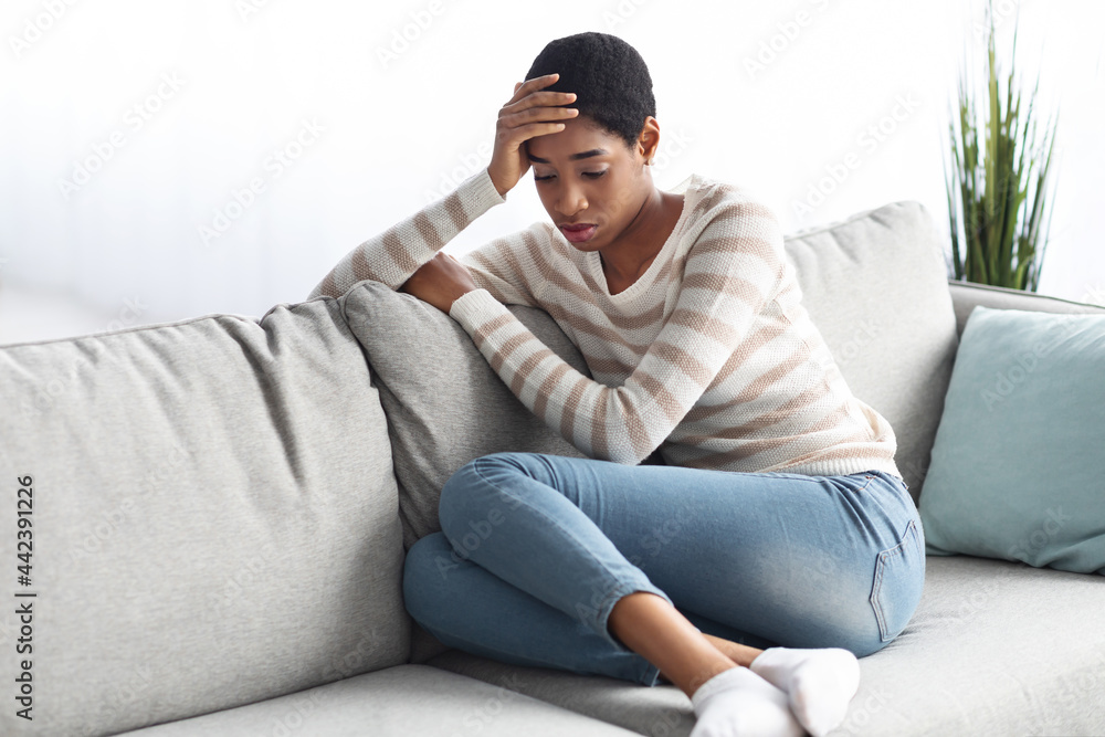 Seasonal Depression. Portrait Of Sad Black Female Sitting On Sofa At Home Seasonal Depression. Portrait Of Sad Black Female Sitting On Sofa At Home